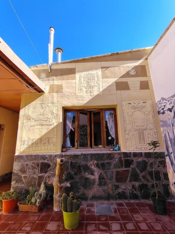 Patio del hostal con pared de piedra, ventana y cielo azul