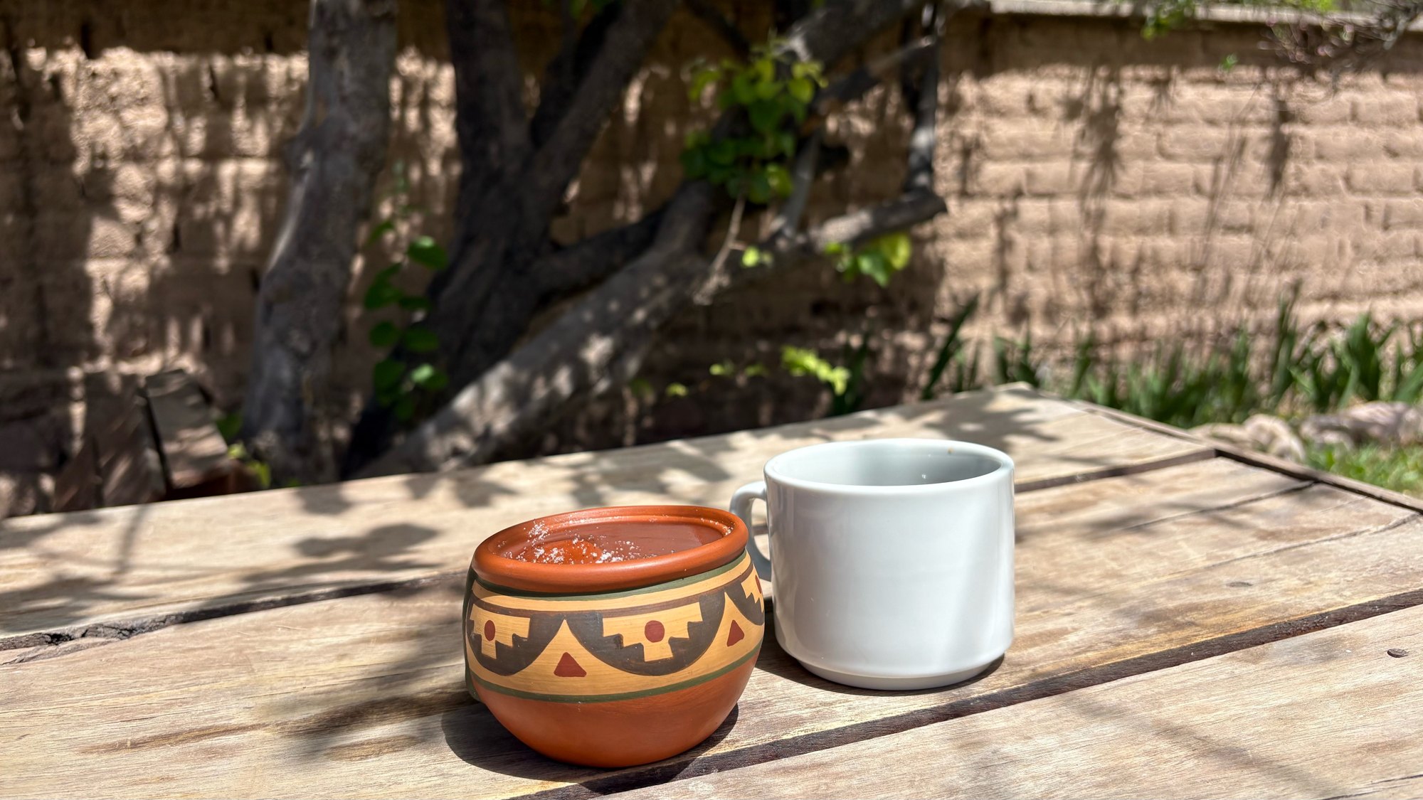Mate de cerámica y taza sobre una mesa de madera en el jardín